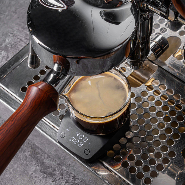 Mini Electronic Coffee Scale from eprolo in action, measuring liquid for coffee preparation on an espresso machine.